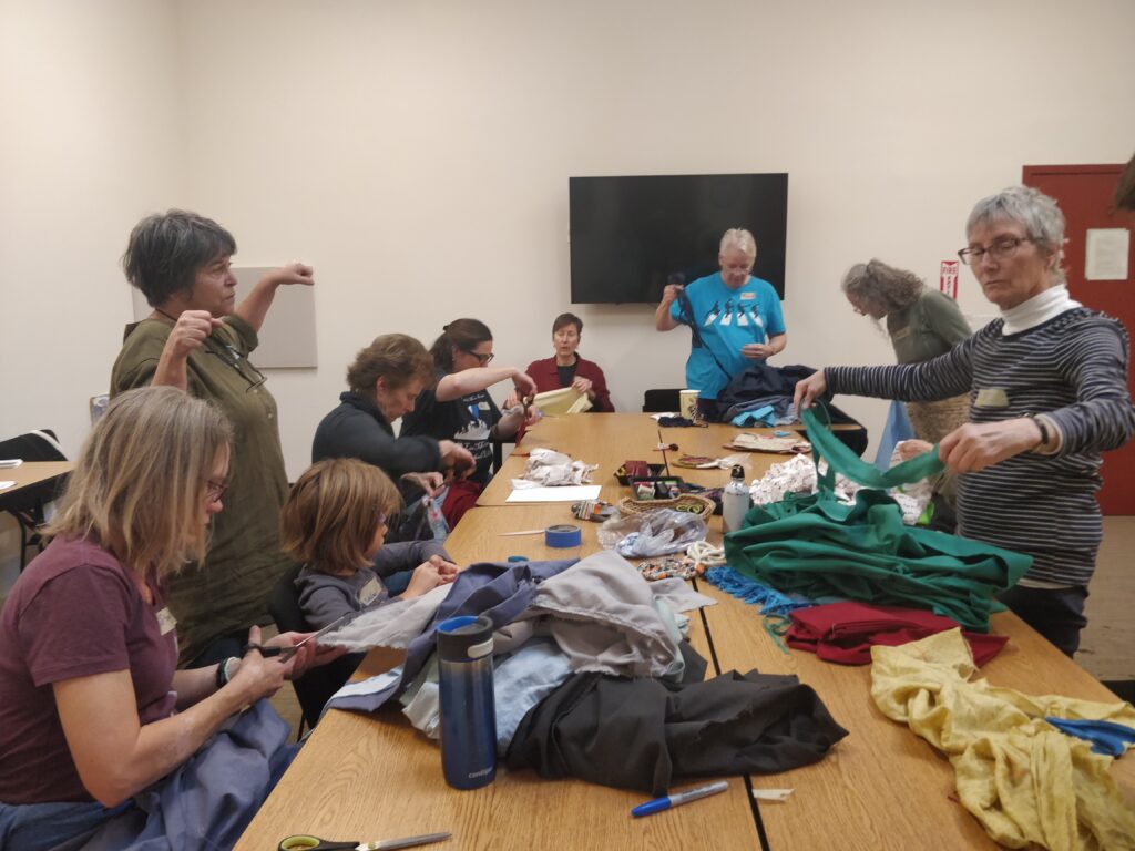 Image of community members learning how to turn scrap fabric into amish knot rugs at an Ecology Center event